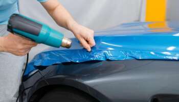 Car wrapping, mechanic with drier installs film Vehicle Color Change Wrap